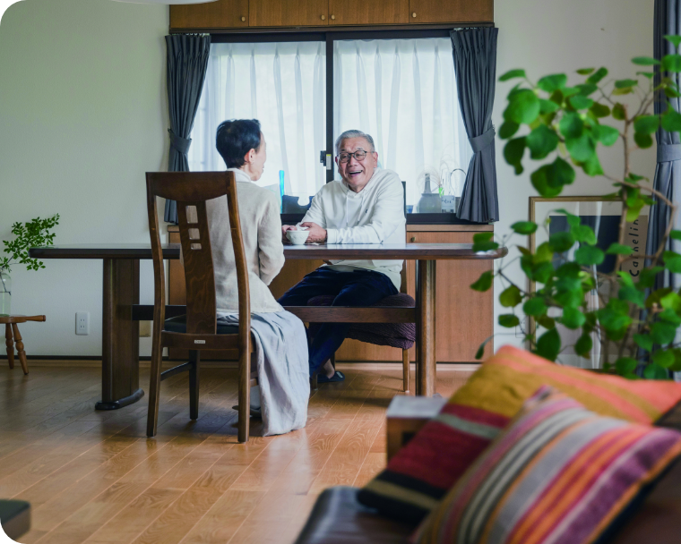 リビングルームのテーブルに座る年配の男性と女性の画像。